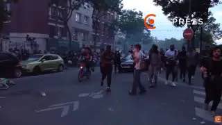 Сотни болельщиков на парижской улице вечером после матча: видны перекрытая дорога, скопление людей и атмосфера беспорядков в городе.