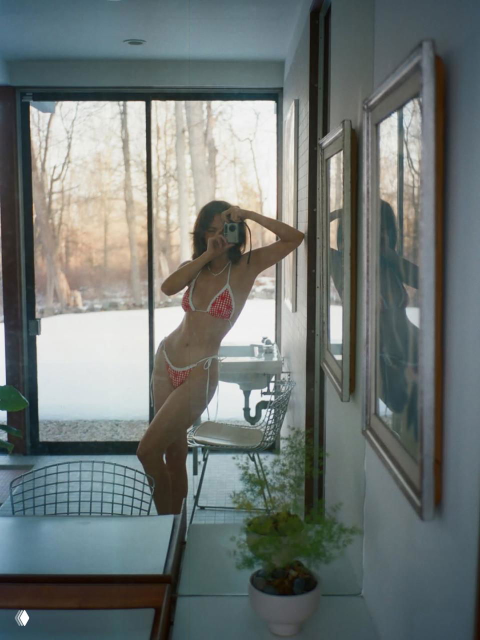 Зеркальный снимок Габриэлы Андрады в красном бикини, отражение и панорамное окно с зимним пейзажем за стеклом, рекламная фотосессия бренда