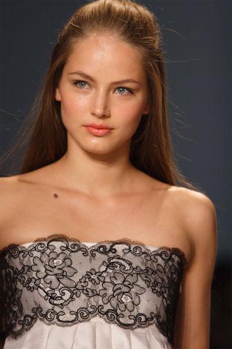 Портретная фотография молодой модели в вечернем образе, снятая крупным планом на нейтральном фоне, естественный свет.