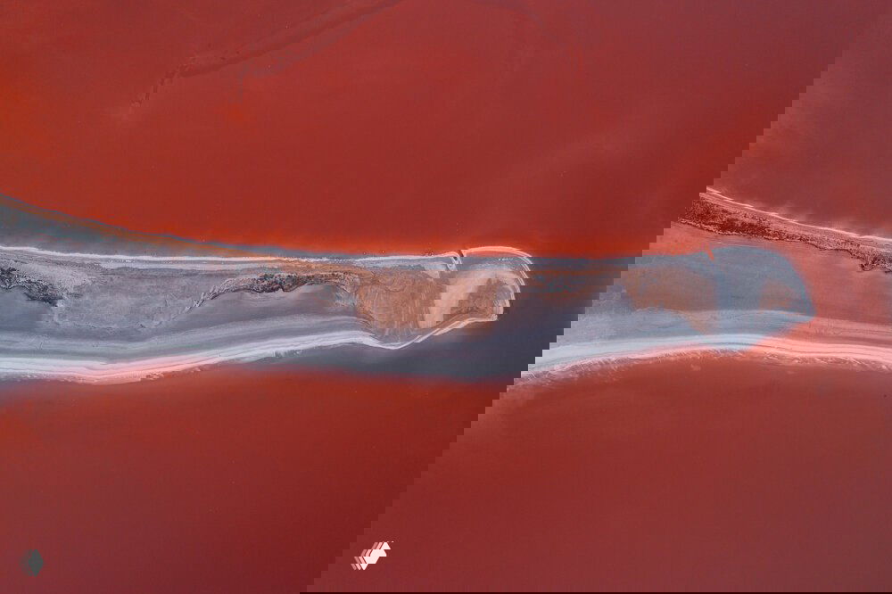 Аэрофотосъёмка узкой солёной косы с насыщенной красной водой и белыми соляными отложениями, вид сверху — авторские кадры Андрея из Крыма.