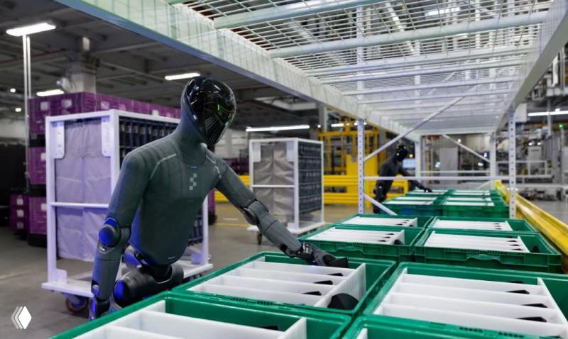 Робот Figure 03 сортирует комплектующие в пластиковые контейнеры на логистической линии завода BMW; видны склады и стеллажи.