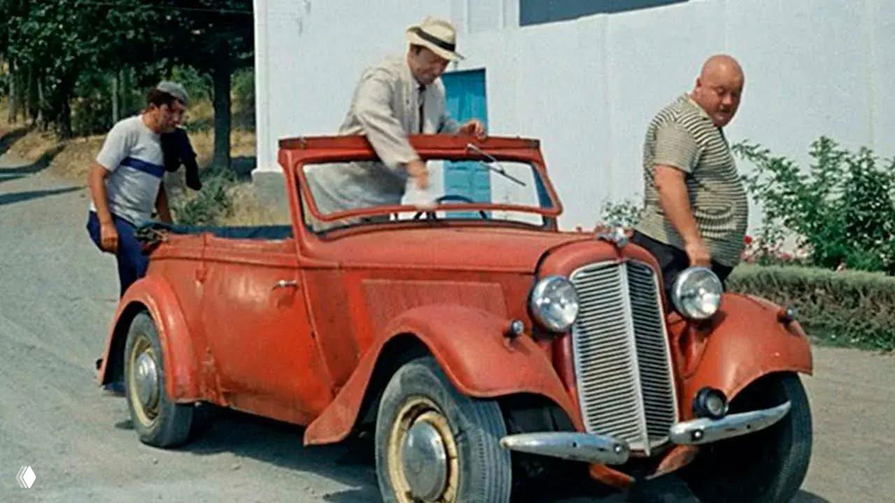 Кадр из «Кавказской пленницы»: красный кабриолет Adler Trumpf Junior на дороге с персонажами Юрия Никулина рядом, винтажный автомобиль.