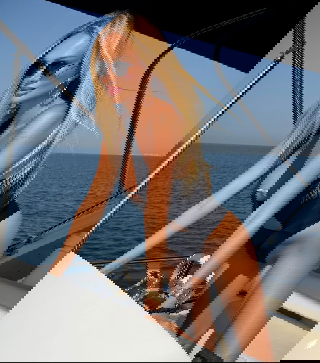 Виктория Лопырева опирается на бортик яхты в черном купальнике, на заднем плане — море и бескрайний горизонт.