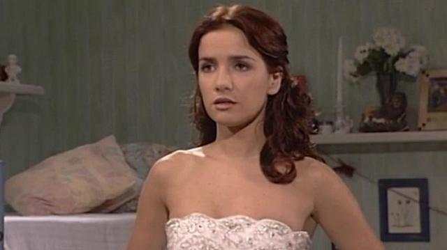 Женщина в белом платье в интерьерной сцене — кадр из телесериала 90-х с нейтральным портретным ракурсом героини на фоне комнаты.