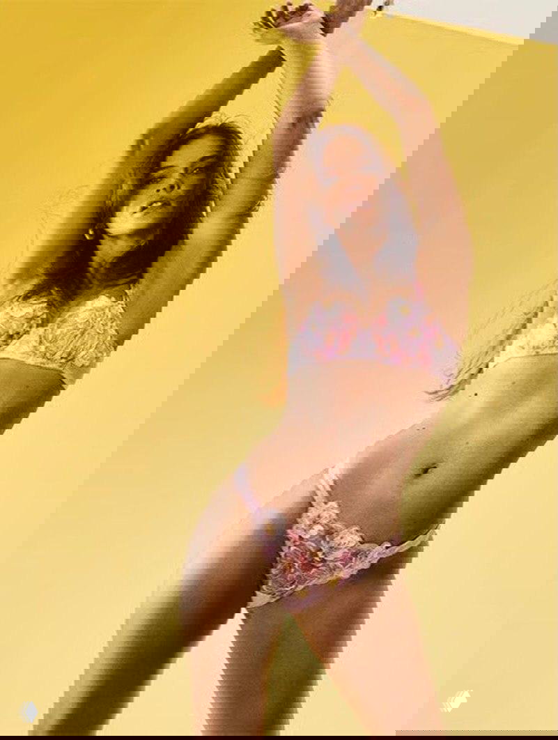 Студийный портретной план: модель в цветочном кружевном комплекте в прыжковой или танцевальной позе на жёлтом фоне, настроение весны и свободы.