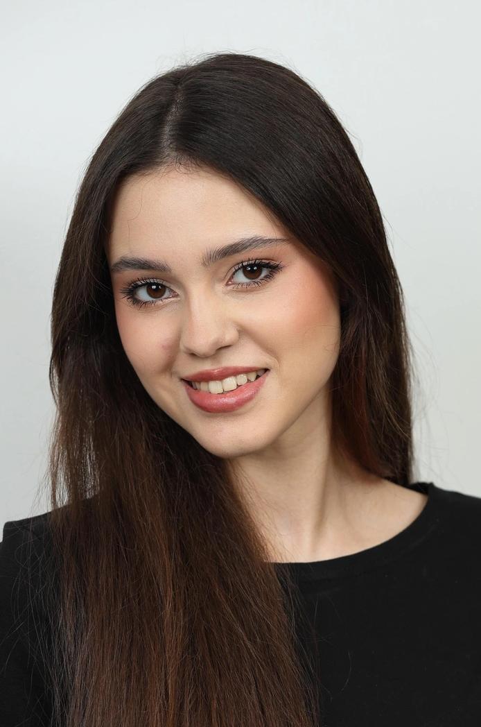 Портрет молодой девушки из списка финалисток «Мисс Татарстан‑2026»: крупный план, тёмные волосы, мягкий макияж и дружелюбная улыбка на светлом фоне.