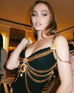 Интерьерный портрет молодой женщины в чёрном платье с золотыми цепями, снимок подчёркивает образ и вечерний стиль.