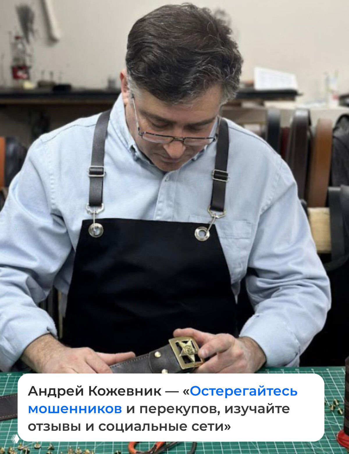 Мастер кожевенного дела в фартуке за рабочим столом, держит пряжку и внимательно обрабатывает кожаный ремень — рабочая сцена в мастерской.