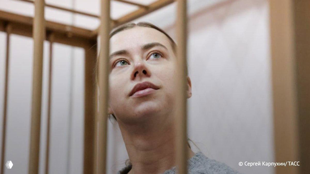 Крупный план женщины за металлическими решётками в зале суда, взгляд направлен вверх — документальная сцена судебного процесса.