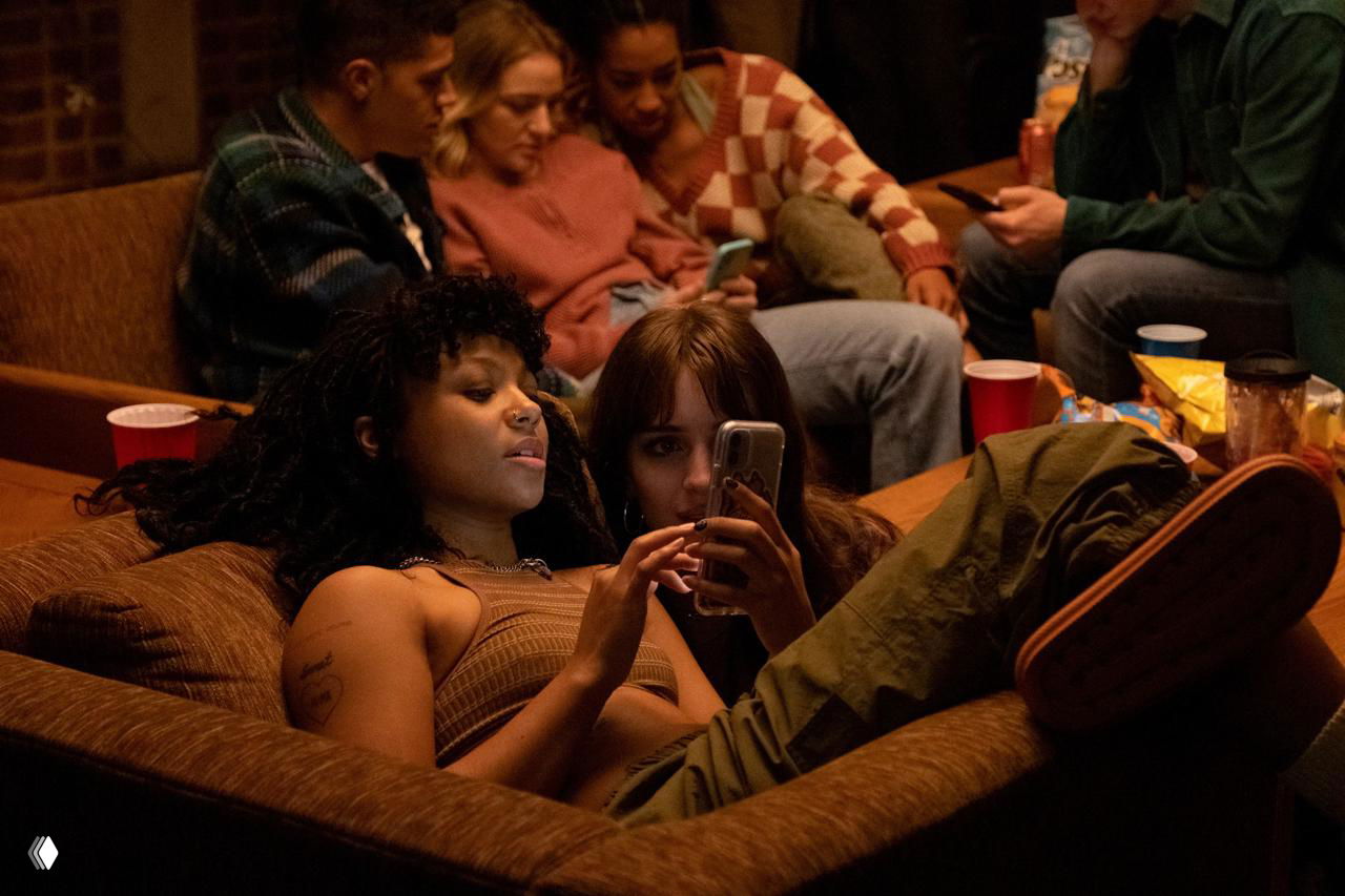 Группа молодых людей на диване в неформальной атмосфере, некоторые смотрят в телефоны — сцена, отражающая онлайн‑сообщество и цифровое взаимодействие между инвесторами.