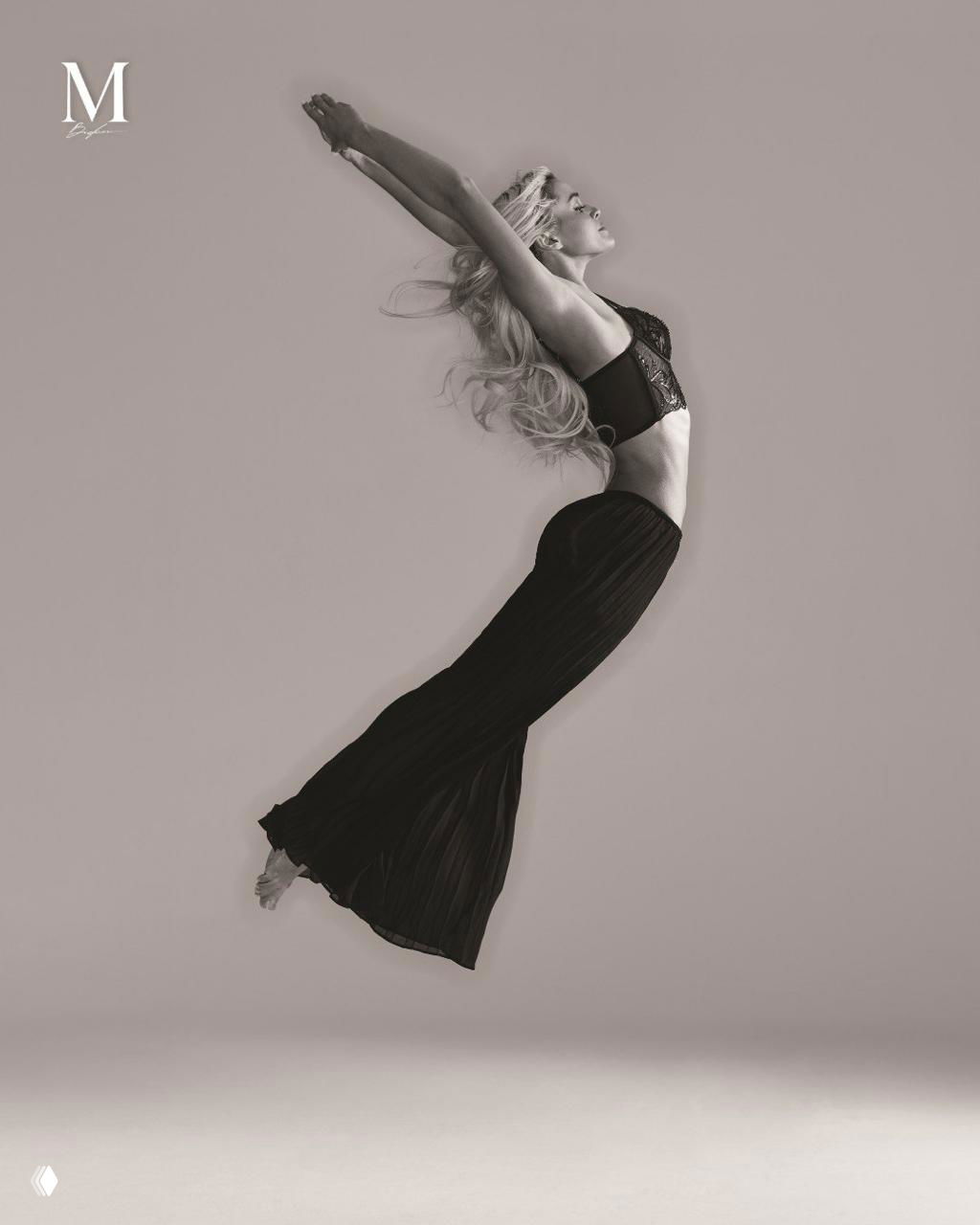 Динамичный чёрно‑белый кадр Ливви Данн в прыжке: легкоатлетка демонстрирует грацию и силу, композиция подчёркивает движение, силуэт и форму тела.