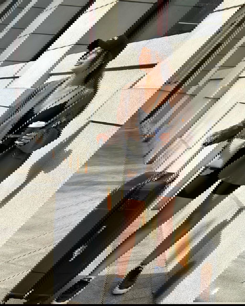 Лилия в повседневном уличном образе с чемоданом в руках; фото показывает стиль, одежду и аксессуары в городской обстановке.