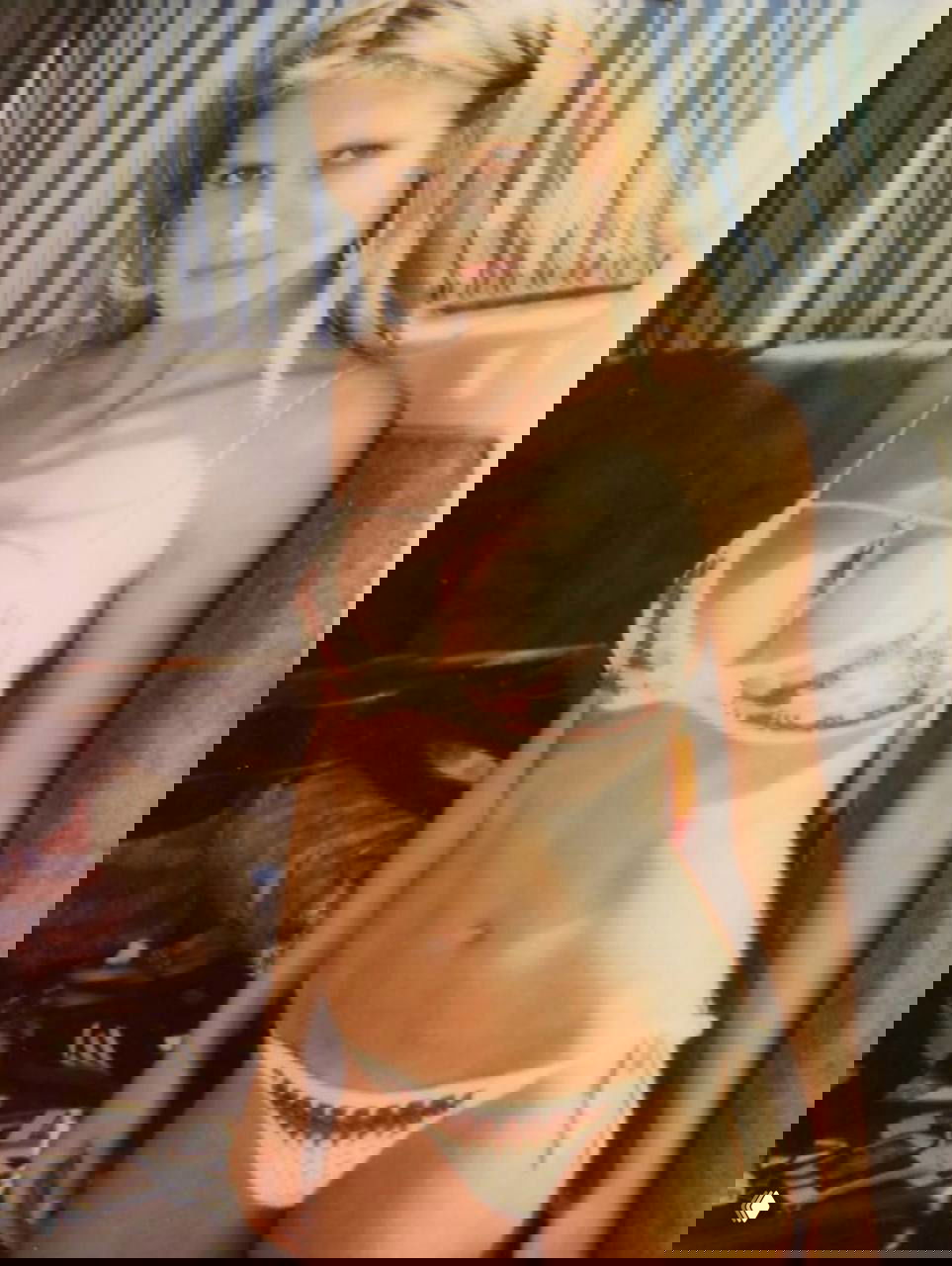 Полароидный по стилю снимок 2000-х: молодая женщина в бикини внутри трейлера, мягкий свет, ностальгическая цветокоррекция и зернистость плёнки.