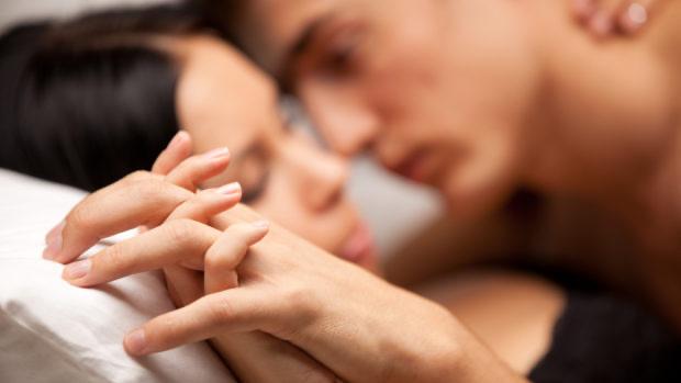 Пара в кровати держит руки — иллюстративное фото к опросу о сексуальных привычках, мастурбации, порно и проблемах интимной жизни россиян.