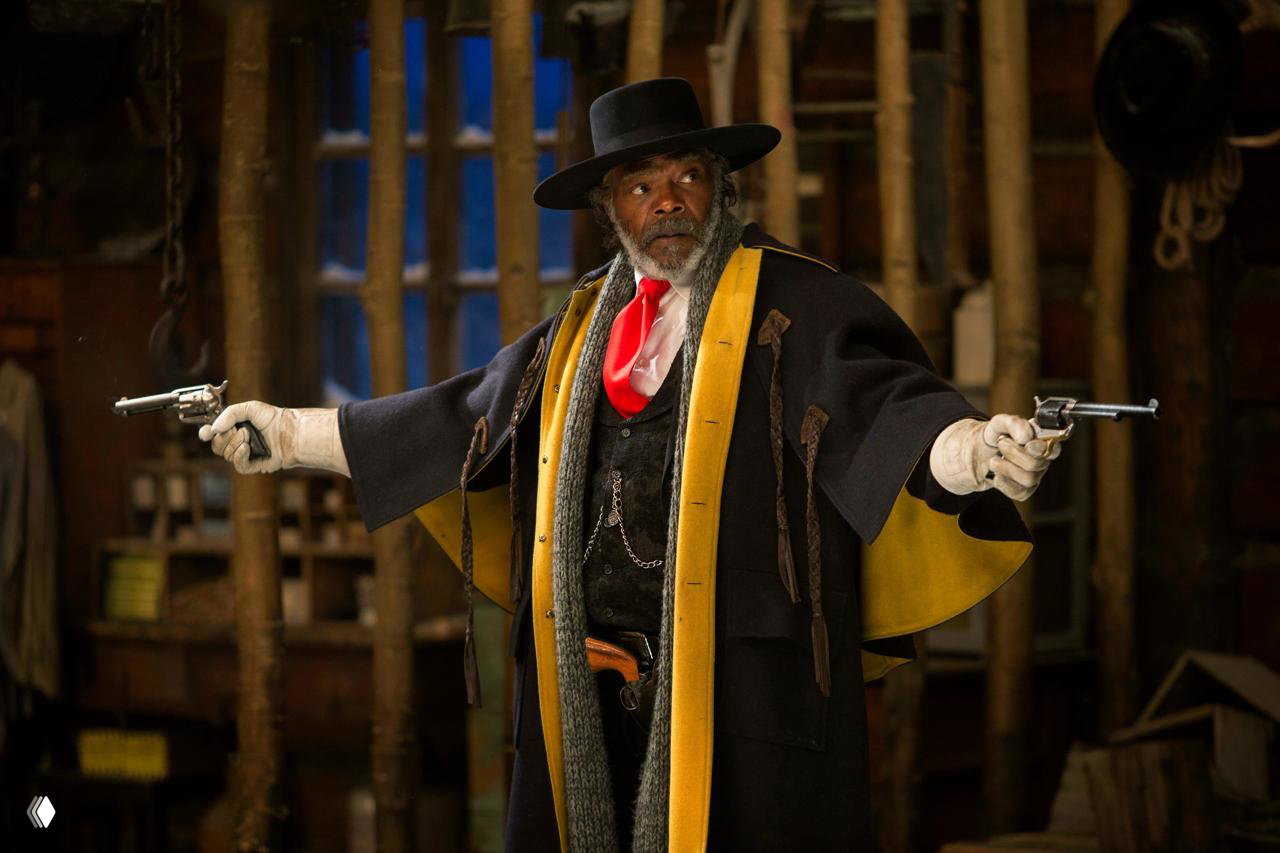 Сэмюэл Л. Джексон в костюме и шляпе из «Омерзительной восьмерки», с пистолетами в руках — энергичный кадр из внутреннего помещения.