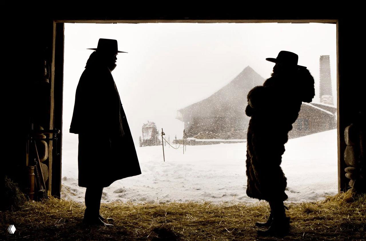 Силуэты двух фигур в дверном проёме на фоне снежного пейзажа и дальнего амбара — контрастный кинематографический кадр вестерна.