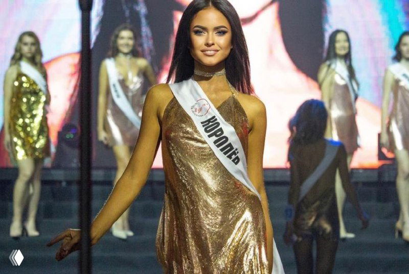 Фотография с артефактами и искажениями файла: изображение конкурсанток и сцены частично повреждено пикселизацией и цветовой размытостью.