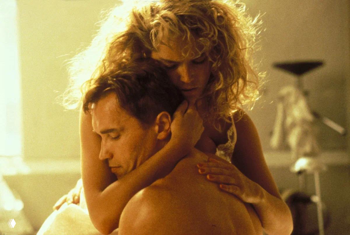 Интимная сцена: женщина обнимает обнажённого мужчину в тёплых тонах — романтический эпизод из художественного фильма.