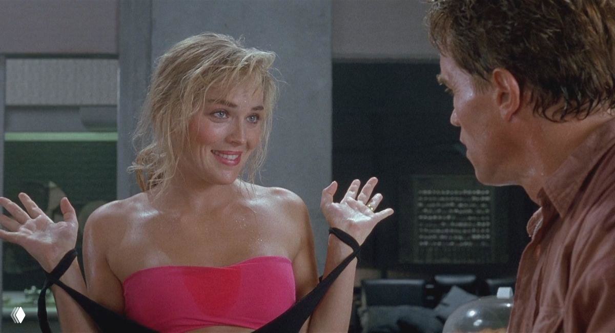 Широкий кадр: женщина улыбается, демонстрируя жесты с поднятыми руками в лабораторном или офисном интерьере — лёгкая комедийная интонация сцены.