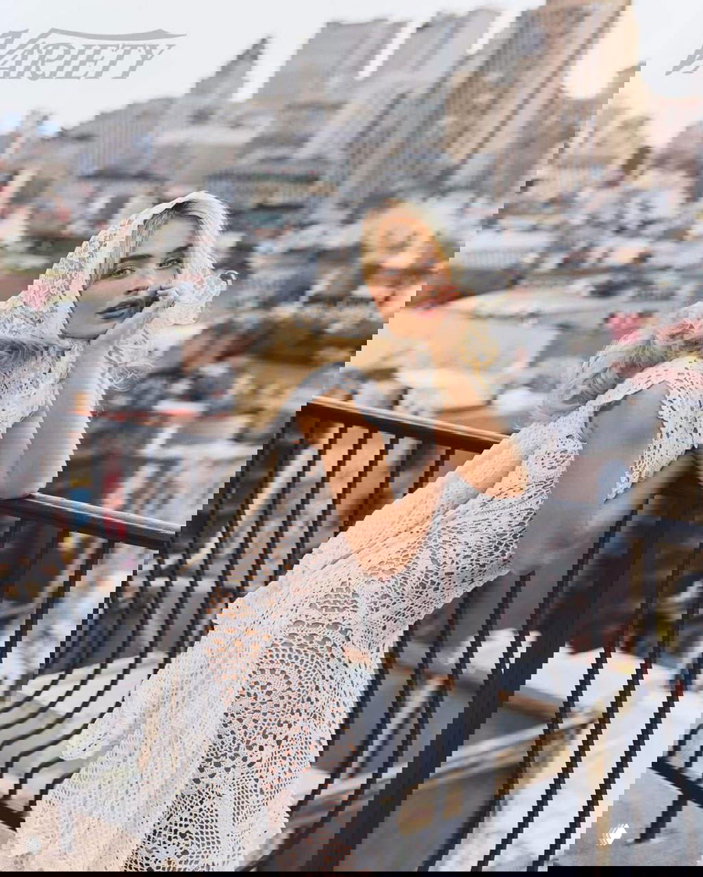 Сабина Карпентер в белом вязаном платье и кружевном платке опирается на перила крыши на фоне городской панорамы, фотосессия Variety.