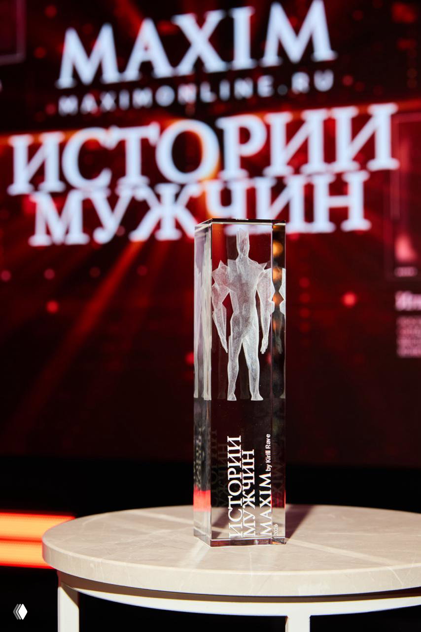 Крупный план хрустальной награды с лазерной гравировкой фигурки на фоне светящейся проекции названия проекта «Истории мужчин».