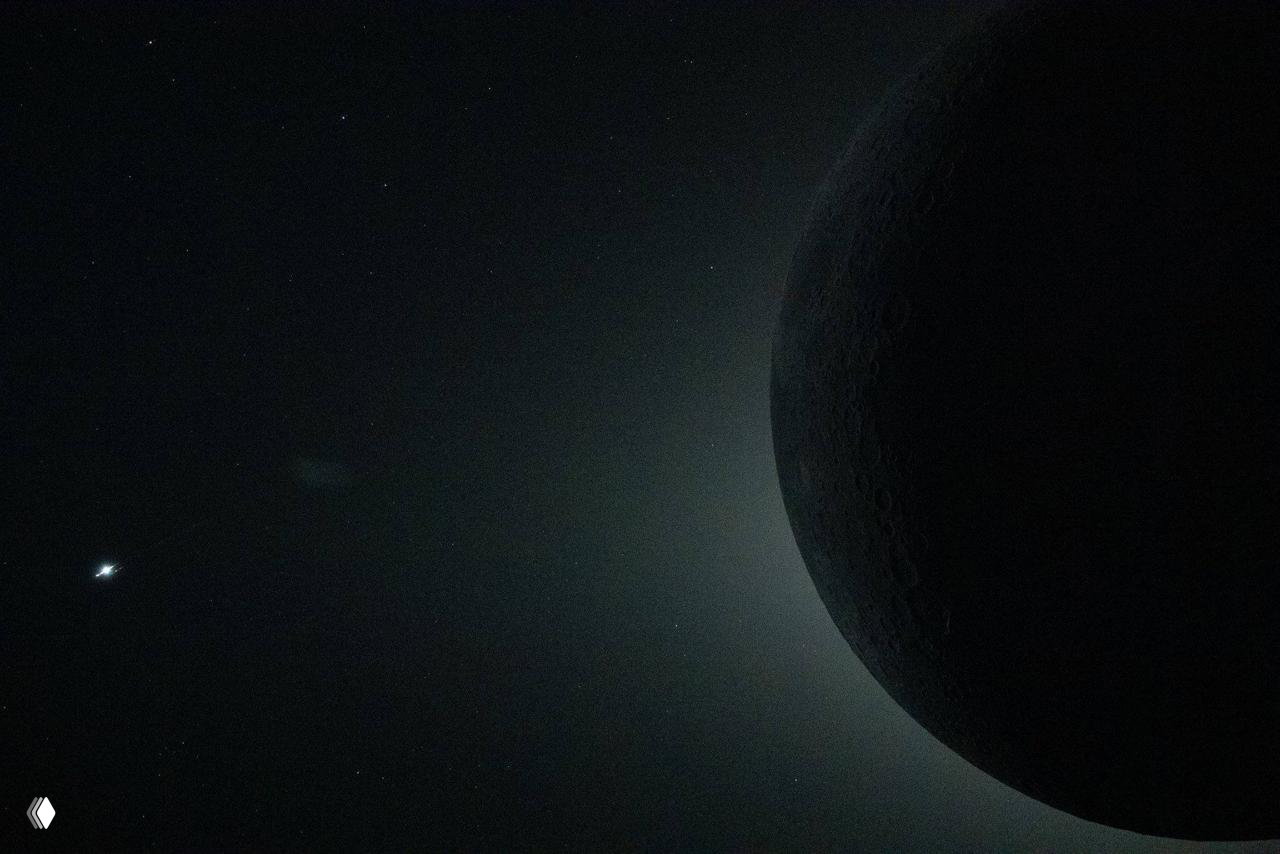 Тёмный край Луны с подсветкой по периферии и звёздным фоном — панорамный художественный кадр, подчёркивающий силуэты и световые эффекты в миссии «Артемида‑2».