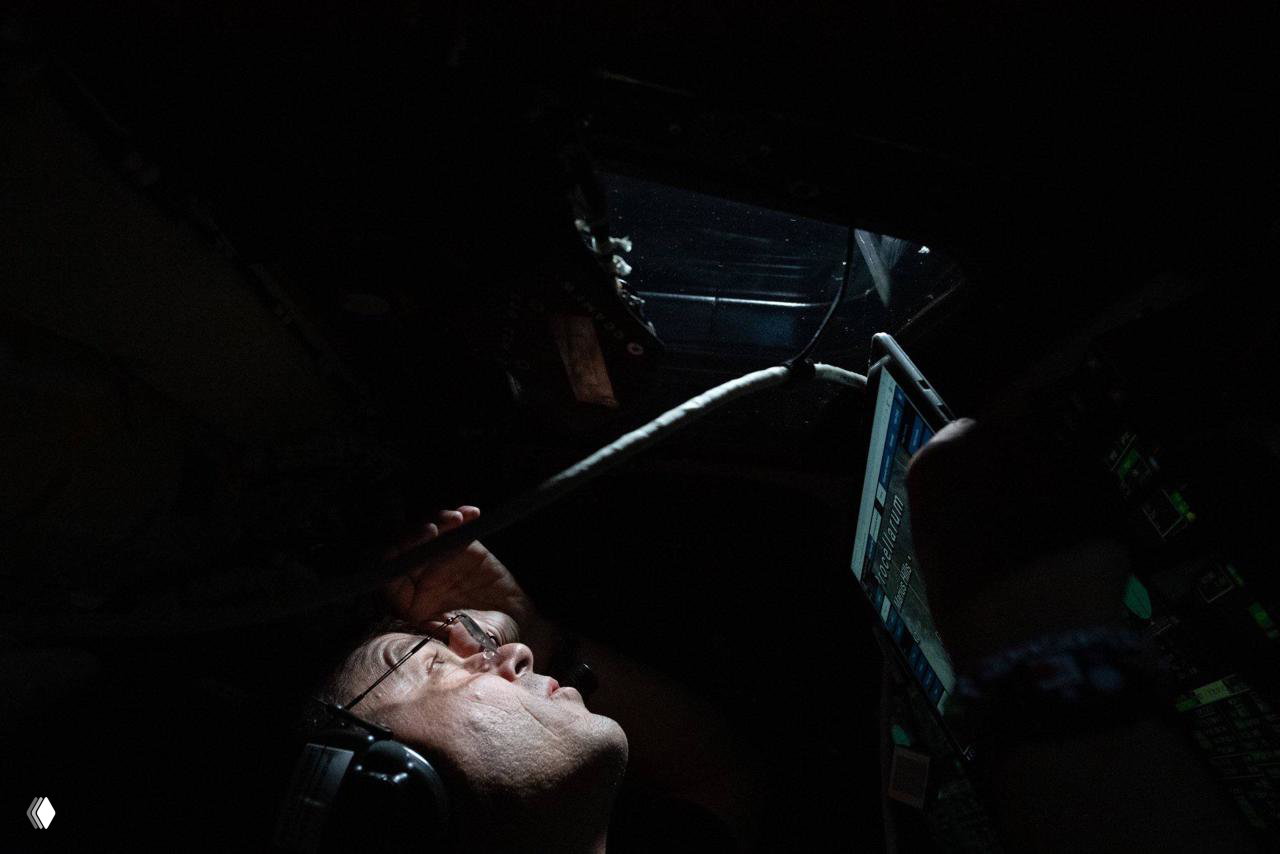 Астронавт в наушниках изучает планшет в кабине, видна часть приборной панели; кадр иллюстрирует навигационную и операционную работу в миссии «Артемида‑2».