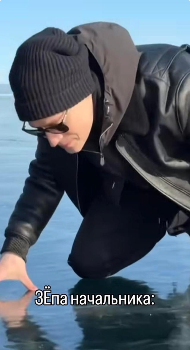 Скрин с молодым человеком в тёмной одежде, наклонившимся над льдом; снизу текстовый юмор и подписи, кадр используется для создания мемов и шуток.