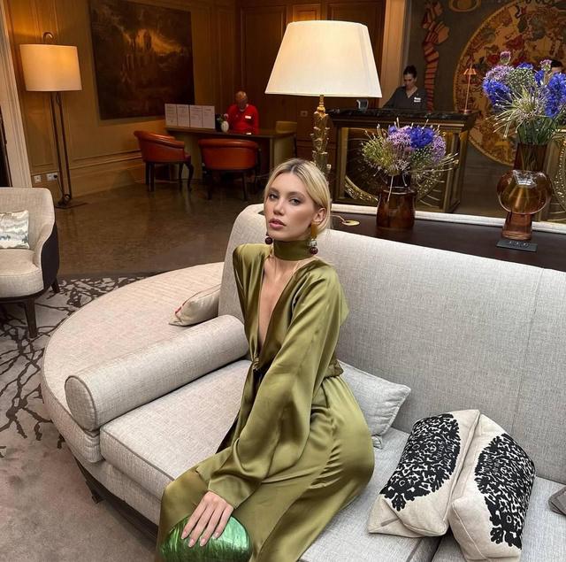 Натали Пушкинова в зелёном шелковом платье позирует на диване в отеле — фотосессия в рамках мероприятий Miss Earth 2025.