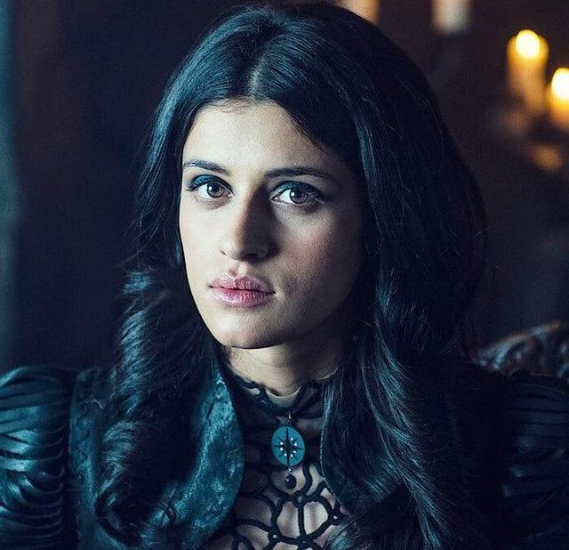 Портретный кадр Ани Чалотры в образе Йеннефер: спокойное лицо, выразительный макияж и причёска, театральный свет и костюмная деталь на фоне интерьера.