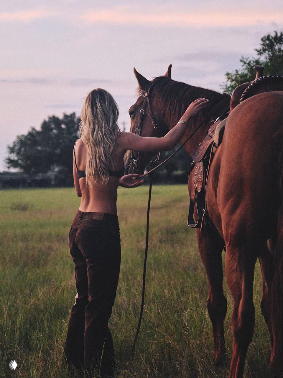 Задний план: модель стоит рядом с лошадью в поле при закате, видно спокойную позу и контакт с животным, пасторальная атмосфера.