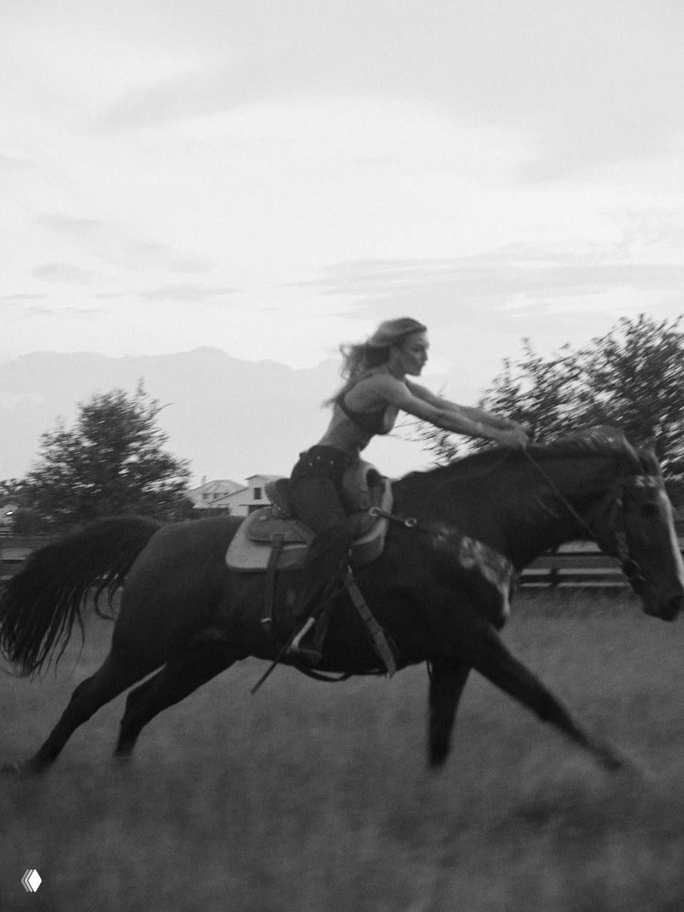 Чёрно-белый кадр с галопирующей лошадью и сидящей на ней женщиной, художественная фотография с выразительной динамикой движения.