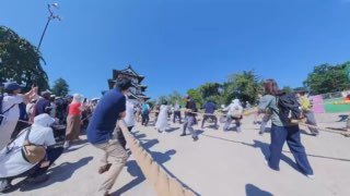 Волонтеры тянут длинные канаты перед старинным замком Хиросаки, участвуя в перемещении здания по рельсам традиционной техникой хикия.