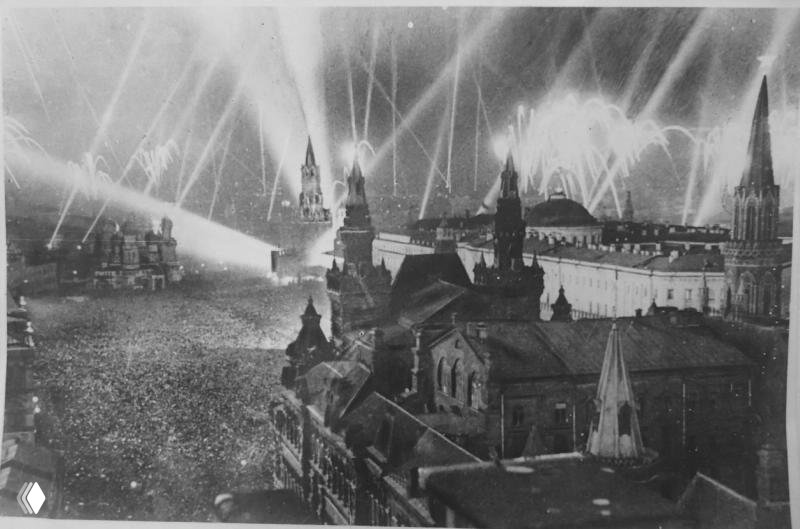 Ночное торжество около Кремля с прожекторами и толпой людей — праздничная иллюстрация массовых торжеств в честь Победы в СССР.