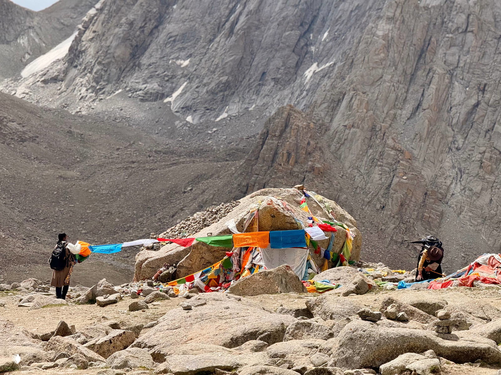 Каменные урочища у подножия гор с многочисленными молитвенными флажками и тропой, по которой идут паломники во время коры вокруг Кайлаша.