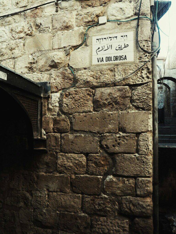 Улица Via Dolorosa в Старом городе Иерусалима: каменные стены, табличка с надписью VIA DOLOROSA и узкий проход, ощущение древности.