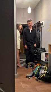Вертикальное короткое видео в прихожей: мужчина и женщина в домашней обстановке, сумки и вещи на полу, лёгкая ироничная сцена утренней жизни.