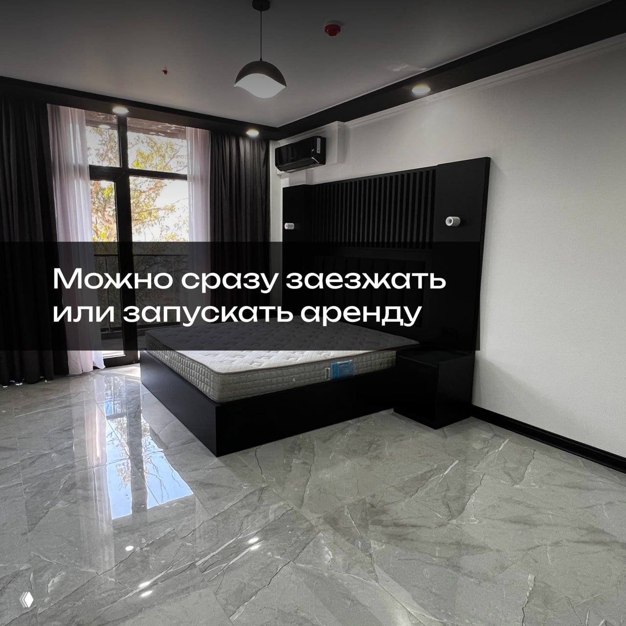 Спальня в готовой квартире: матрас, ночные тумбы, большое окно с выходом на балкон; состояние готово к заселению и сдаче.