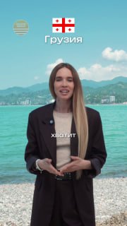 Женщина-ведущая на фоне моря и гор в Шекветили: кадр у береговой линии с пляжем и горами, на изображении также видна эмблема и подпись.
