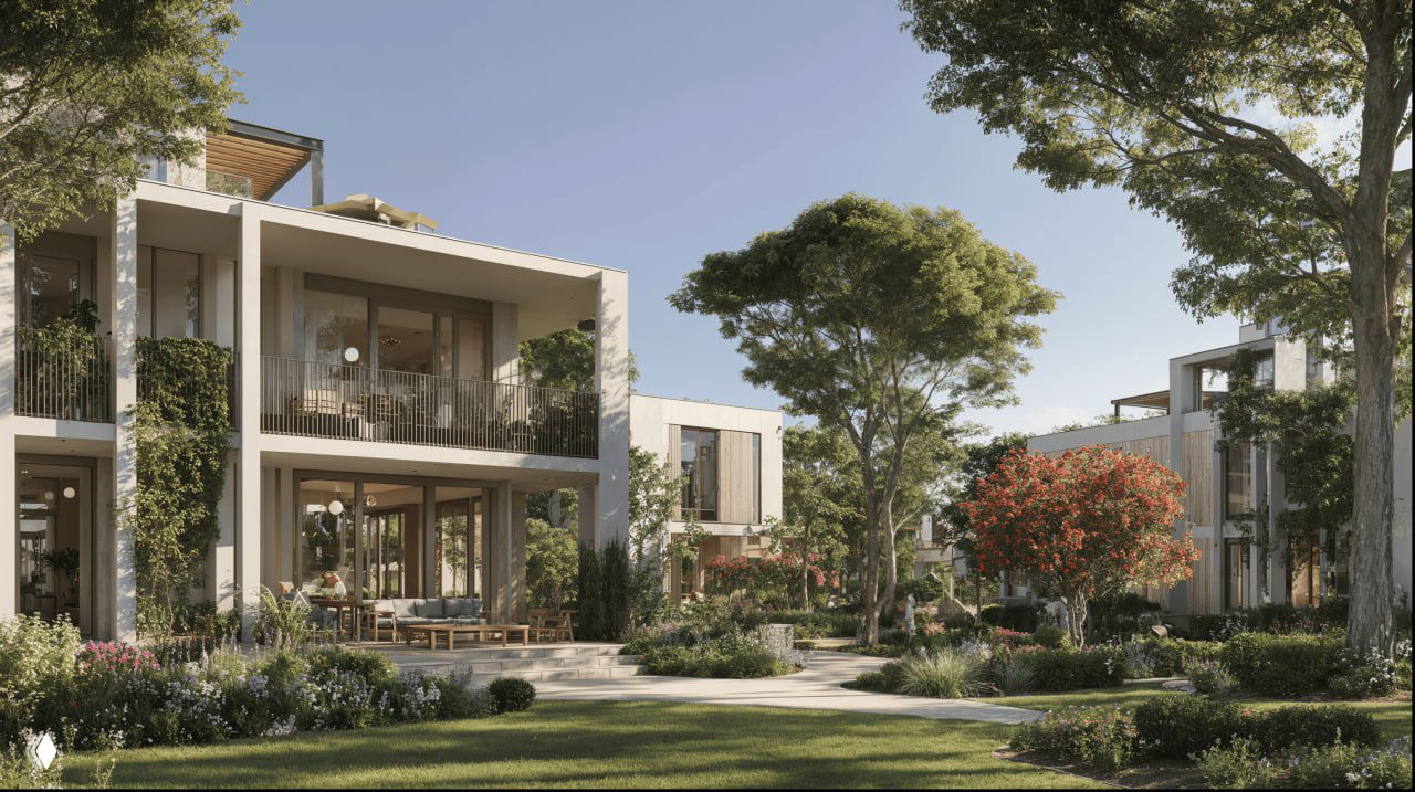 Фасады современных низкоэтажных апартаментов с террасами, цветущие насаждения и ухоженные газоны вокруг зданий комплекса.