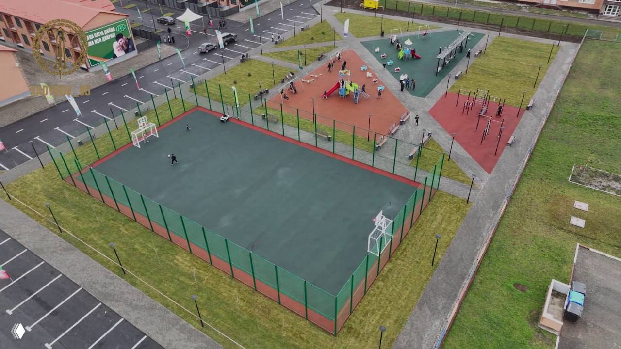 Панорамный вид сверху на спортивную площадку, игровые зоны и парковки в новом жилом комплексе таунхаусов в Грозном.