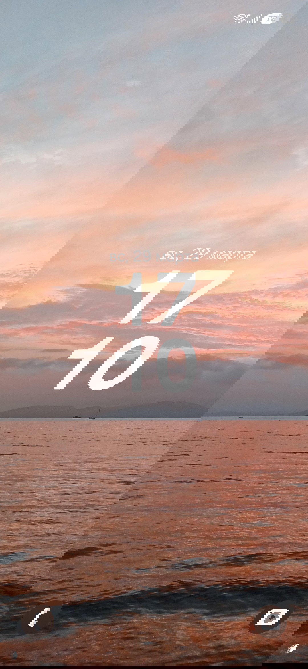 Розово-оранжевый закат над морем с тихой гладью воды и силуэтом парусника — тёплая весенняя обложка для экрана блокировки.