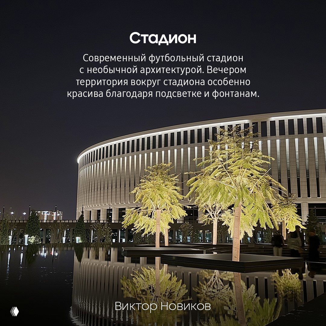 Современный футбольный стадион в Краснодаре вечером, подсветка и фонтаны на переднем плане, отражения в водной глади и прогулочная зона.