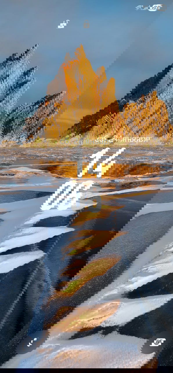 Вертикальная фотография скалистой морской бухты и льда на переднем плане, тёплый свет заката подчёркивает текстуры — для мобильной заставки.