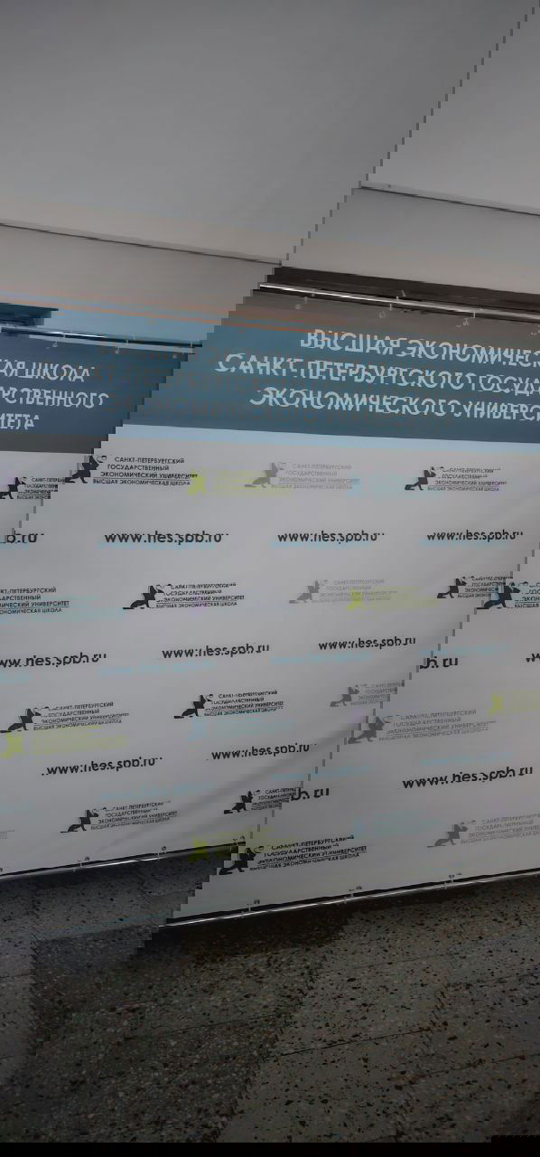 Пресс-волл Высшей экономической школы Санкт‑Петербургского государственного экономического университета с логотипами и адресом сайта, стенд в фойе.