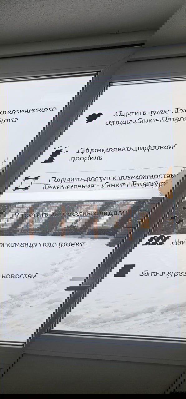 Дверное стекло с перечислением преимуществ технопарка Санкт‑Петербурга и видом заснеженного внутреннего двора за окном — визуал локации на Петроградке.