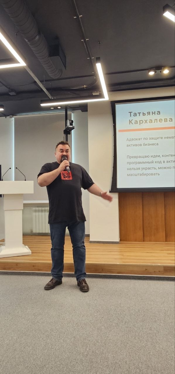 Павел Никифоров выступает на сцене с микрофоном у экрана, рассказывая про сарафанное радио и оцифровку рекомендаций.