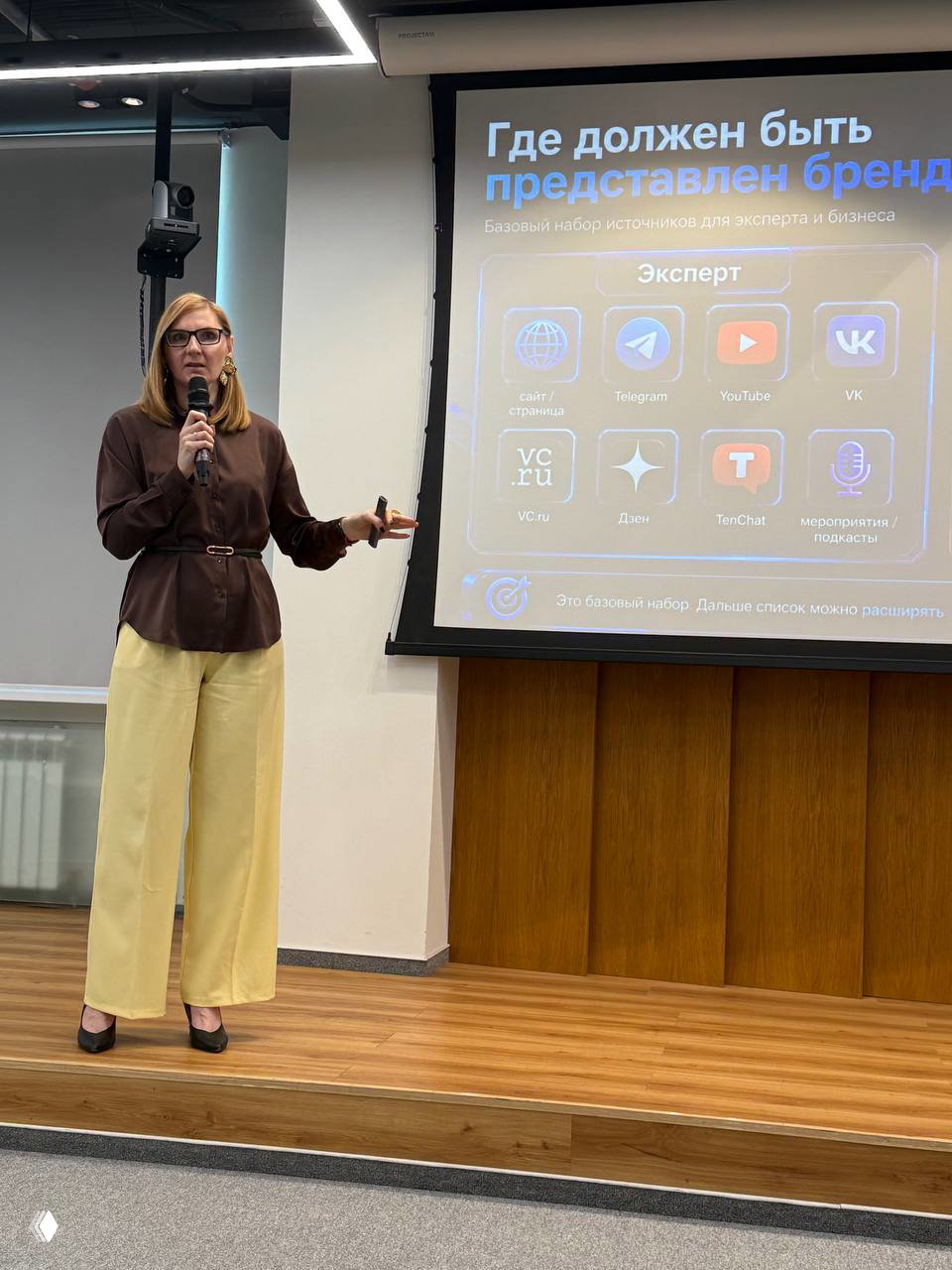 Спикерка у экана с слайдом «Где должен быть представлен бренд», перечисляющая каналы для эксперта: сайт, Telegram, YouTube и др.