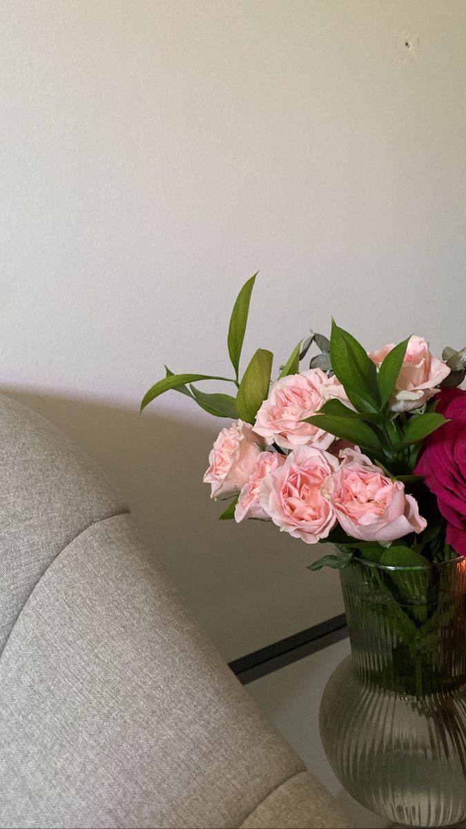 Фрагмент интерьера со свежим букетом в вазе рядом с креслом — декоративный элемент офисного или домашнего рабочего пространства бухгалтера.