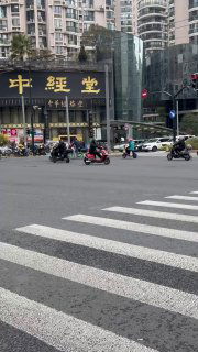 Уличный кадр перекрёстка с пешеходным переходом, мотоциклы и люди на улицах Шанхая, городская повседневная сцена с дорожным движением и вывесками.